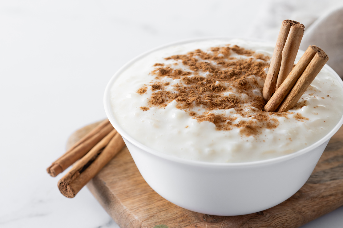 Arroz con leche. Rice pudding with cinnamon in clay bowl on white marble
